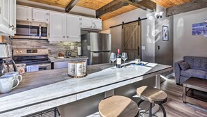 A modern kitchen with white cabinets, stainless steel appliances, and a large island with stools.
