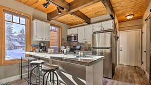 A modern kitchen with a large island, bar stools, and a view of a snowy landscape.