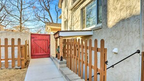 A residential property with a red gate, wooden picket fence, and a concrete pathway leading to a house with a stone facade. - 3 Mi to Dtwn: Convenient Denver Apt (Denver)