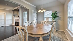 A dining area with a wooden table and chairs, a chandelier, and a fireplace.
