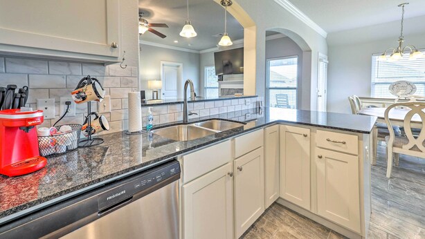 A modern kitchen with white cabinetry, a granite countertop, and a red coffee maker.