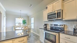 A kitchen with white cabinets, a stainless steel stove, a microwave, and a coffee maker.