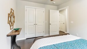 A bedroom with a bed, a ceiling fan, and white double doors.