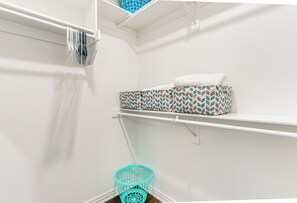 Un área de lavandería con una pared blanca, una repisa con un cesto de ropa de diseño y una toalla blanca sobre una estantería.