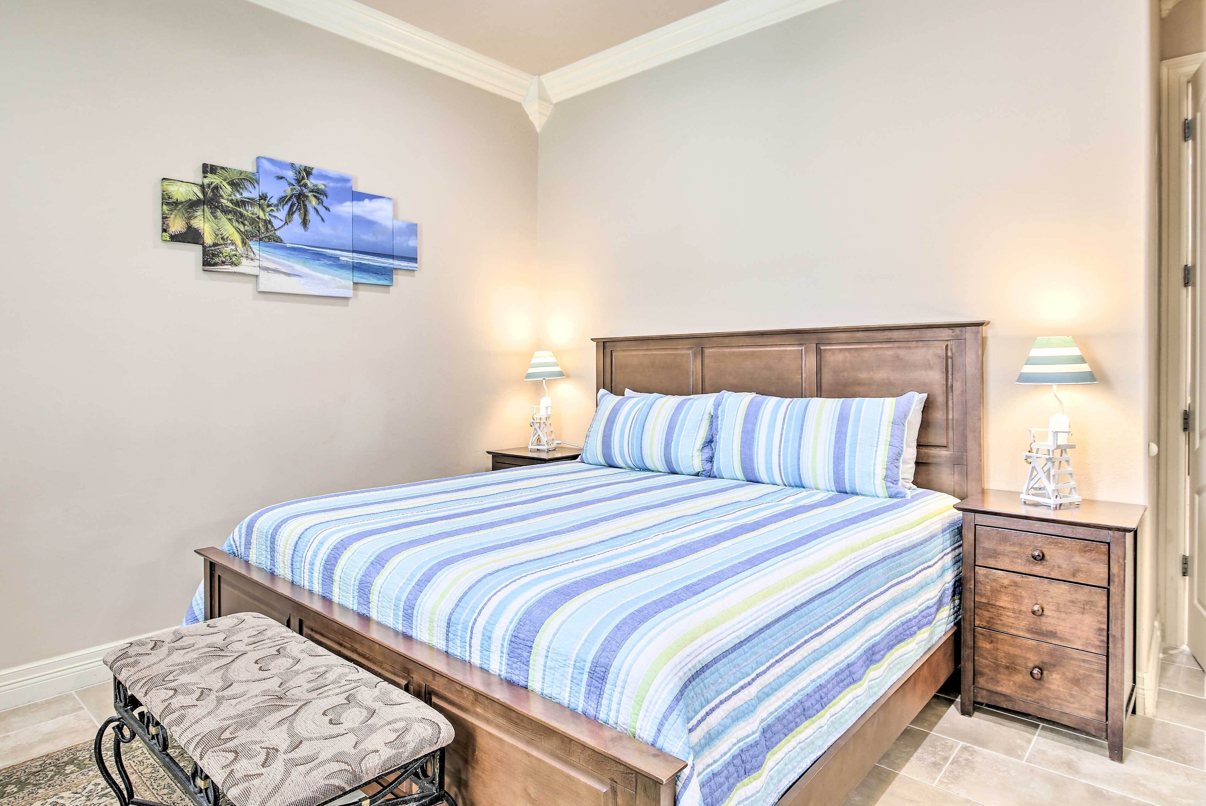 A bedroom with a bed, nightstands, a bench, and wall art.
