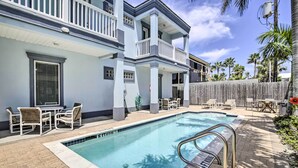 A pool area with a pool, lounge chairs, and a wooden fence. - South Padre Island Condo - 200 Ft to Beach! (South Padre Island)