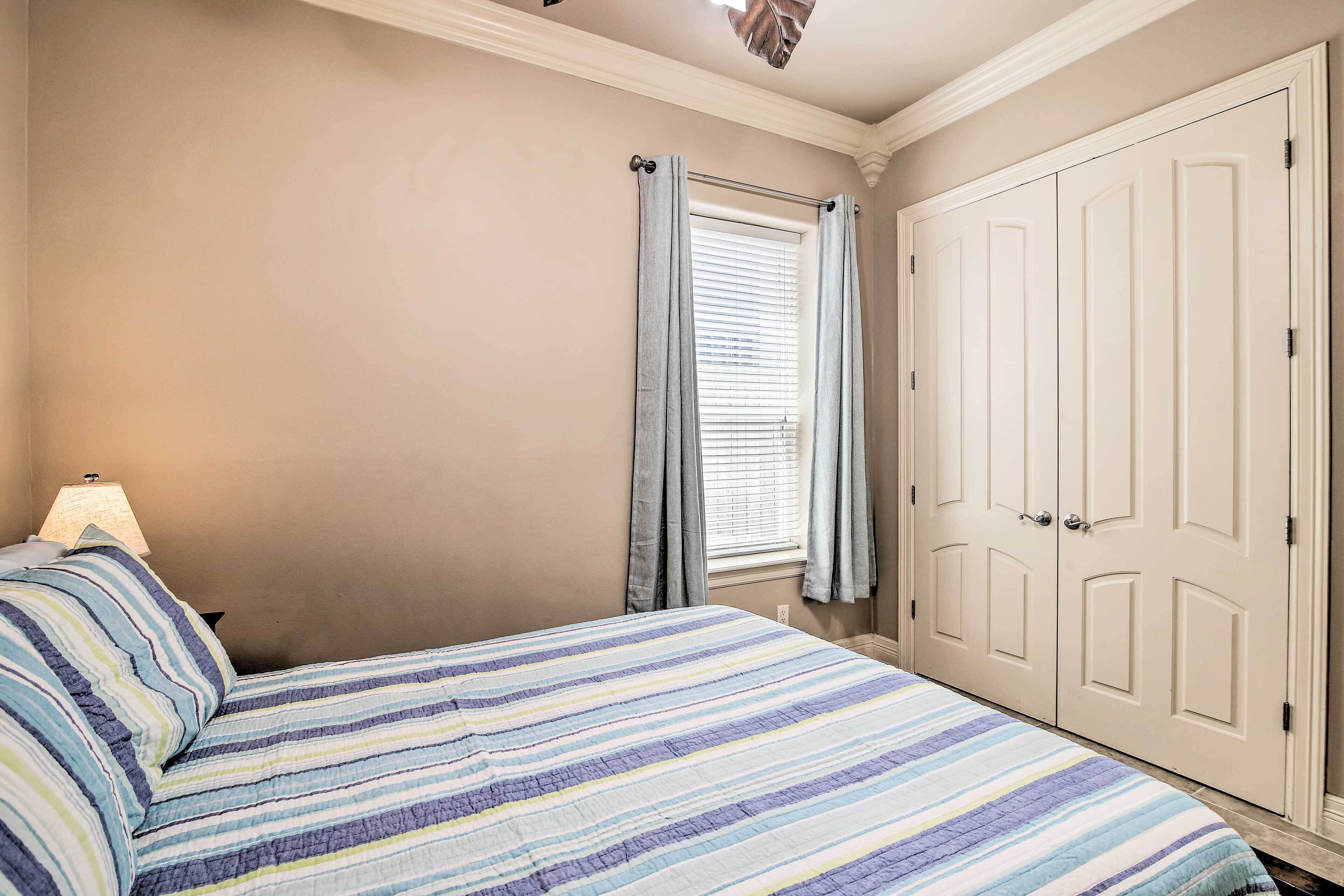 A bedroom with a bed, a window with curtains, a lamp, and a wardrobe.