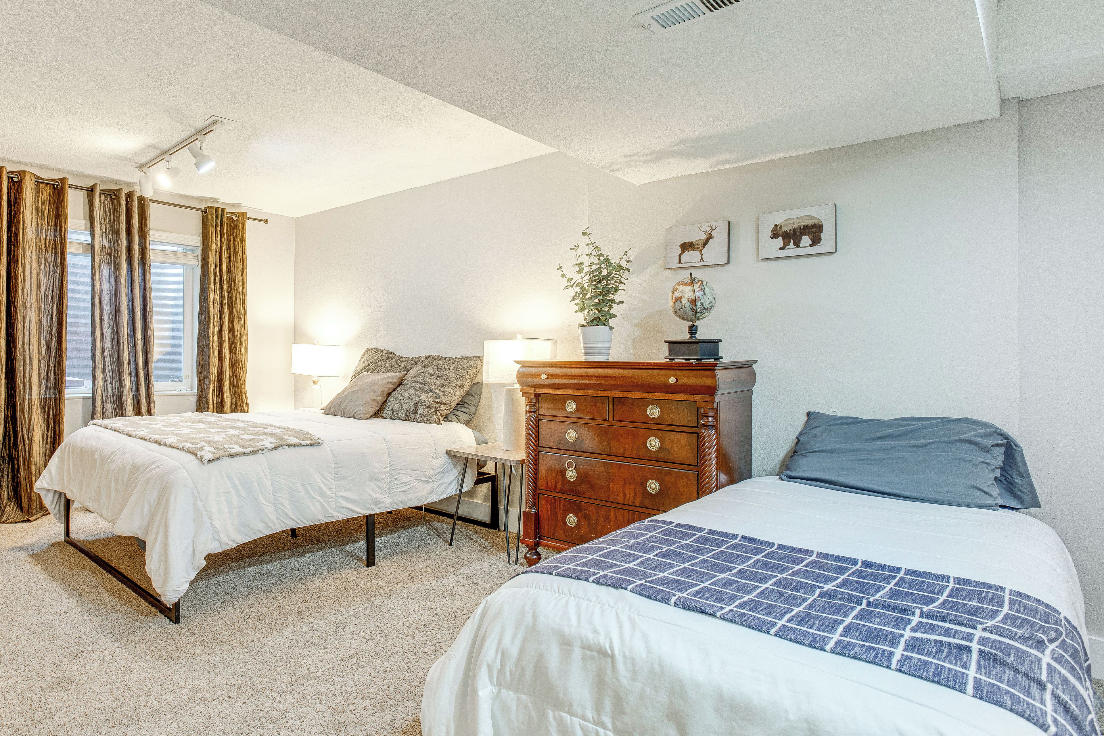 A bedroom with two beds, a dresser, a lamp, and a globe on the dresser.