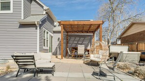 En terrasse med udendørs møbler, et pergola og et bålsted.