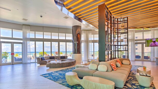 A spacious living area with a large sofa set, a coffee table, and a view of the ocean.