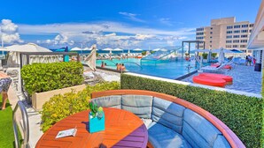 A poolside area with a seating area, a pool, and a view of the ocean.