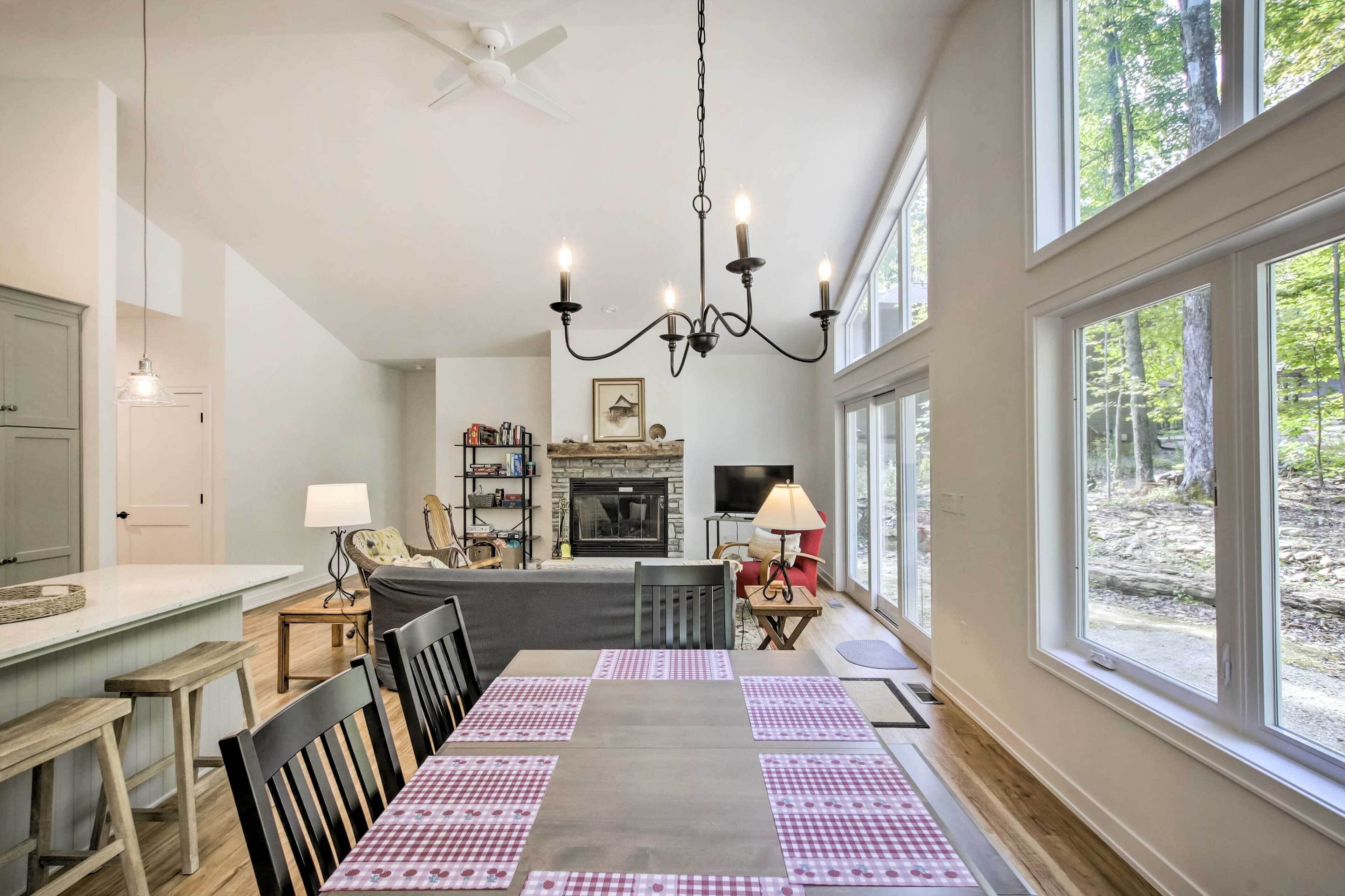 A dining area with a table set for four, a chandelier, and a fireplace in the background.