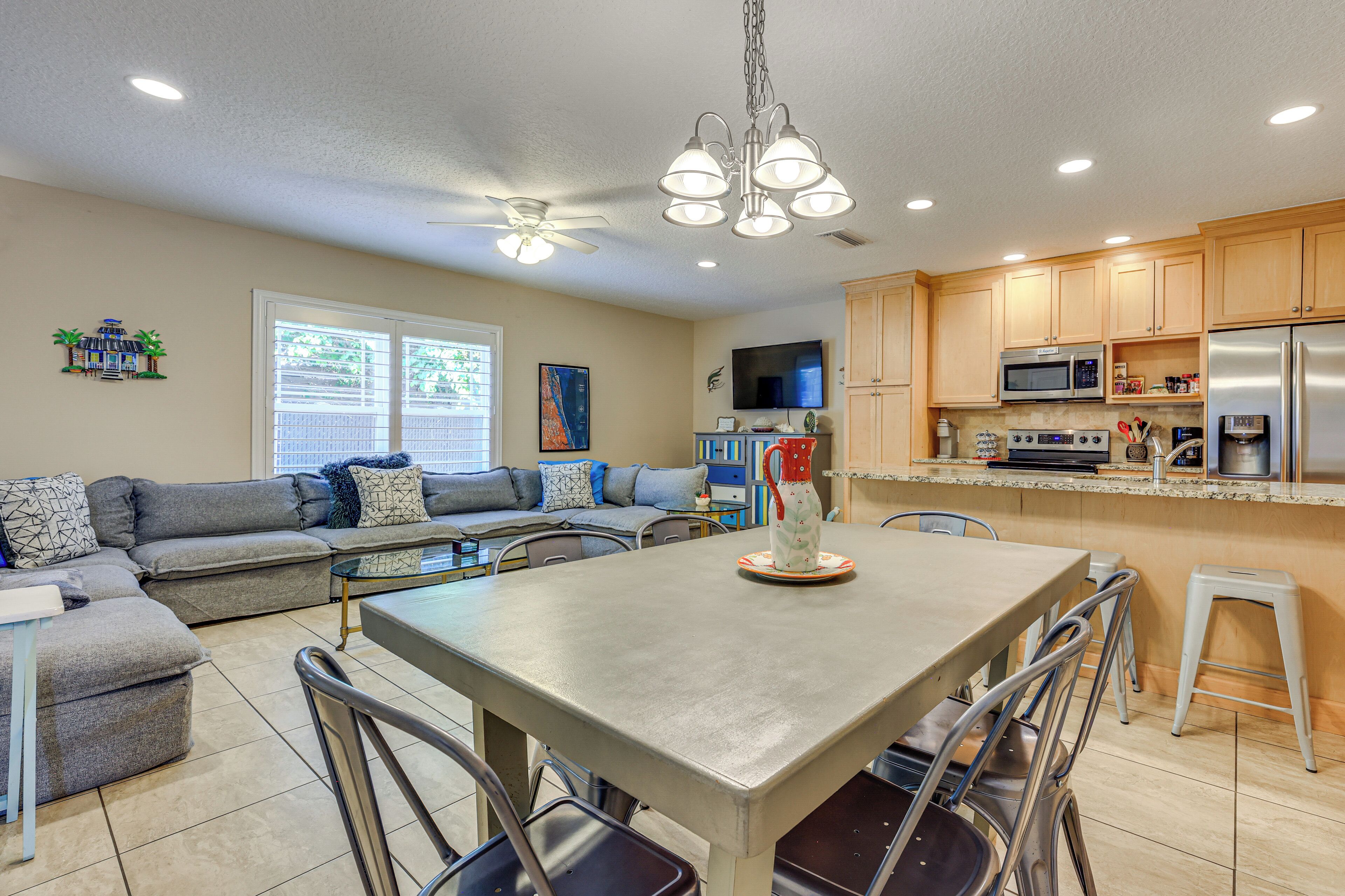 A modern kitchen with wooden cabinets, stainless steel appliances, and a dining area with a table and chairs.