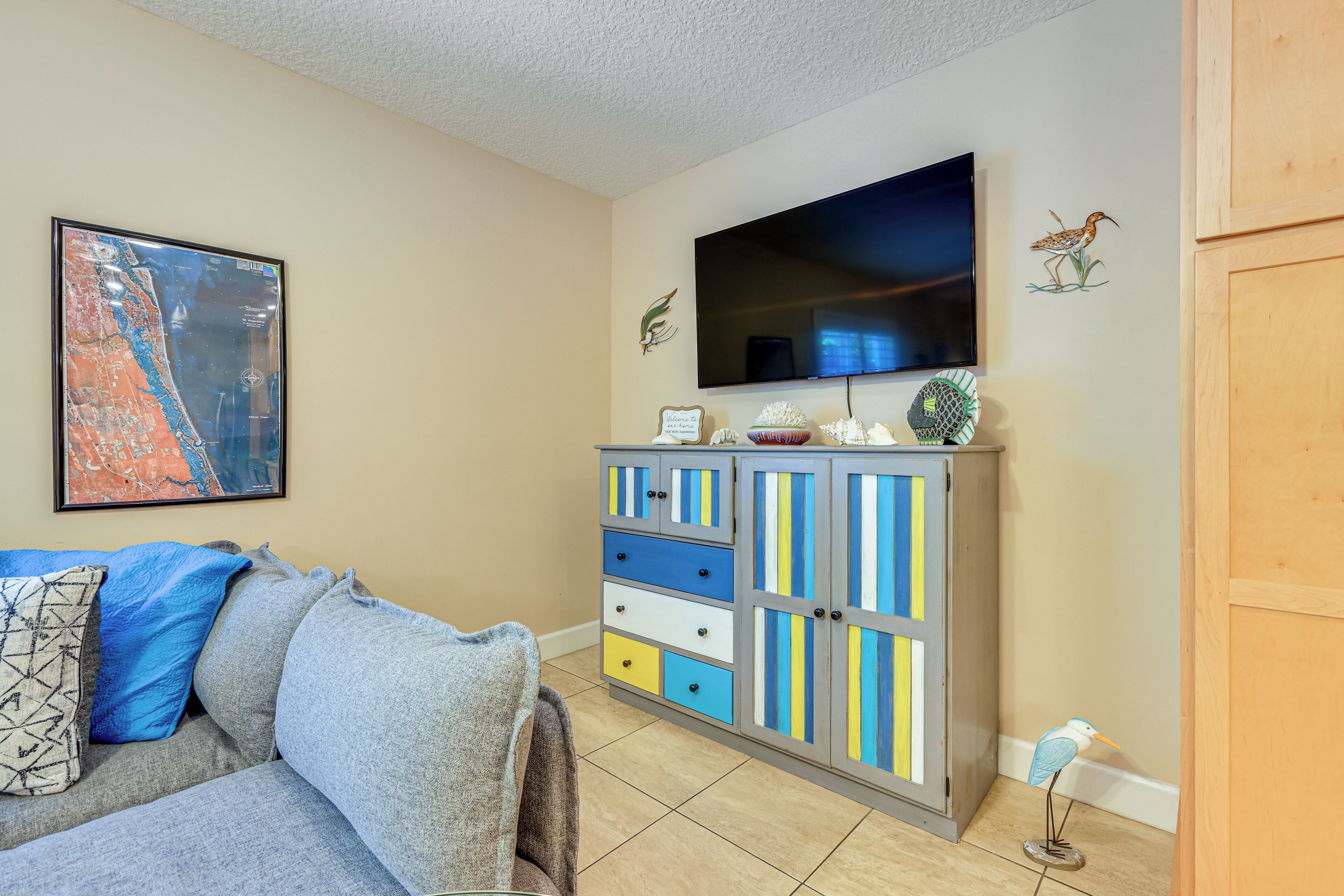 A living room with a sofa, a cabinet with drawers, a flat-screen TV, and wall art.