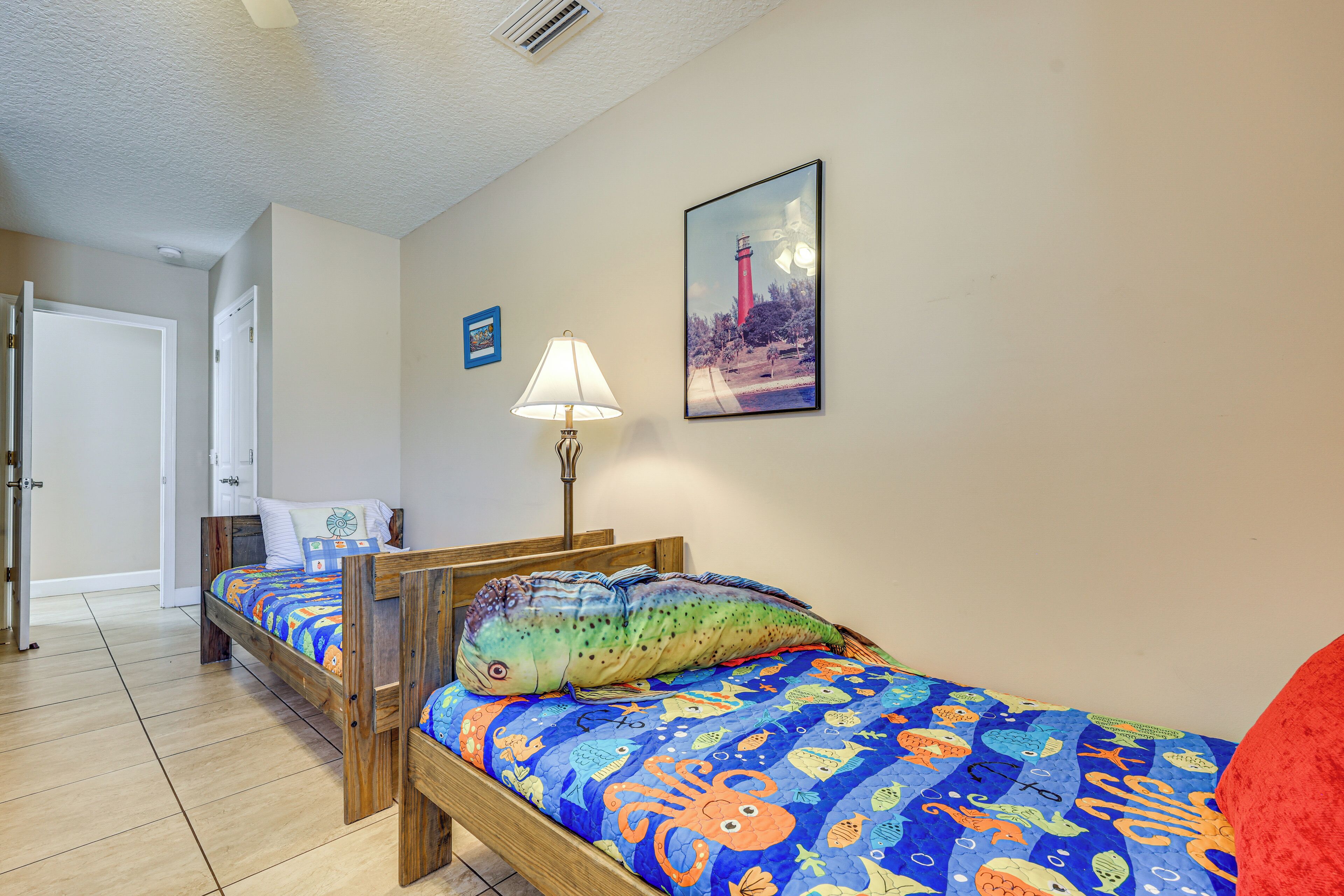 A room with two wooden beds, a nightstand, a lamp, and a framed picture on the wall.