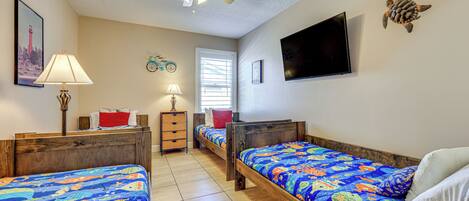 A bedroom with two wooden beds, a ceiling fan, a TV, and a window with blinds.