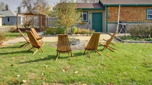 A backyard with four wooden chairs arranged in a semi-circle, a wooden deck, and a house with a green door and windows. - Quaint Ironton Getaway w/ Fire Pit, Gas Grill! (Ironton)