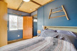 A bedroom with a wooden ceiling, a bed with a striped blanket, a wooden ladder on the wall, and a window with a view of trees. - Fish, Hike & Mtn Bike: Ironton Escape w/ Fire Pit (Ironton)
