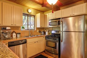 A kitchen with stainless steel appliances, wooden cabinets, and a granite countertop. - Spacious Groveland Cabin w/ Wraparound Deck! (Groveland)