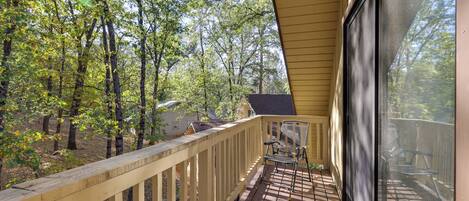 A wooden deck with a railing, overlooking a forested area.