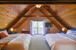 A bedroom with two beds, a ceiling fan, a window with curtains, and a nightstand with a lamp. - Spacious Groveland Cabin w/ Wraparound Deck! (Groveland)
