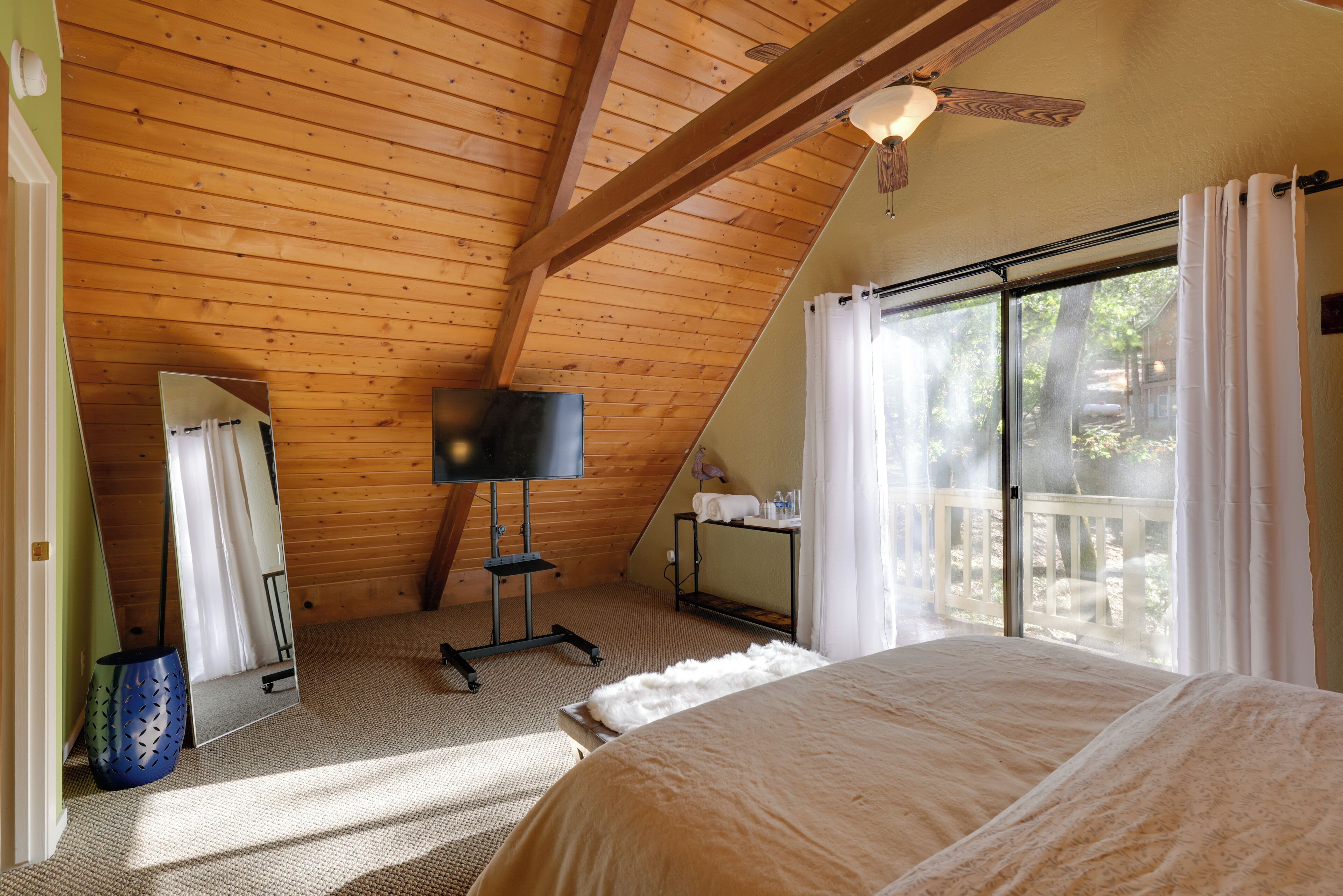 Ein Schlafzimmer mit einem großen Bett, einem Deckenventilator, einem Spiegel und Blick ins Freie.