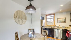 A modern kitchen with a round dining table, wooden chairs, a hanging pendant light, a refrigerator, and a dishwasher. - Telluride Condo: Walk to Lift, Bear Creek, & More! (Telluride)
