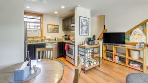 A compact kitchen with modern appliances, a dining area with a round table, and a living space with a television and shelves. - Telluride Condo: Walk to Lift, Bear Creek, & More! (Telluride)