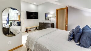 A bedroom with a bed, a TV, a dresser, a bench, and a door. - Telluride Condo: Walk to Lift, Bear Creek, & More! (Telluride)