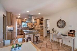 A spacious kitchen with wooden cabinets, a central island, and a large wall clock. - Buena Vista Oasis w/ Mtn Views, 3 Mi to Dtwn! (Buena Vista)