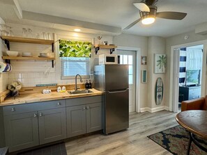 Una cocina moderna con armarios grises, un refrigerador de acero inoxidable y una encimera de madera.