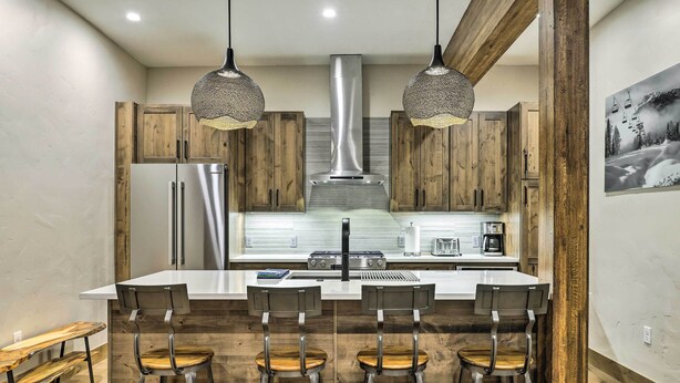 A modern kitchen with wooden cabinets, stainless steel appliances, and a central island with bar stools. - Winter Park Condo w/ Shuttle to Slopes! (Winter Park)