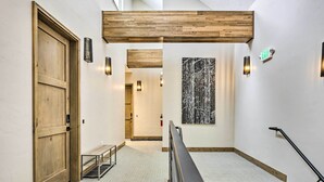A hallway with a wooden door, a bench, a staircase, and a wall-mounted artwork. - Winter Park Condo w/ Shuttle to Slopes! (Winter Park)