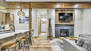 A modern kitchen with wooden cabinets, a bar area with stools, a fireplace, and a seating area with a sofa. - Winter Park Condo w/ Shuttle to Slopes! (Winter Park)