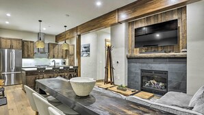 A modern kitchen with a large island, stainless steel appliances, and a flat-screen TV mounted above the fireplace. - Winter Park Condo w/ Shuttle to Slopes! (Winter Park)