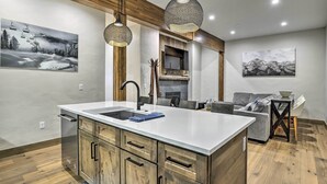 A modern kitchen with a large island, wooden cabinets, and pendant lighting. - Winter Park Condo w/ Shuttle to Slopes! (Winter Park)