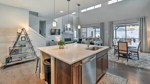 A modern kitchen with a central island, stainless steel appliances, and a dining area with a view. - Granby Golf Retreat w/ Ski Trails, Mountain View! (Granby)