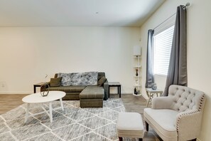 A living room with a sofa, ottoman, and a white coffee table.