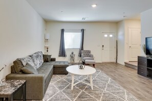 A modern living room with a sectional sofa, a round coffee table, and a television on a stand.