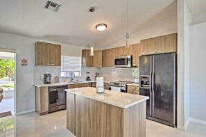 Een moderne keuken met houten kasten, een centraal eiland, roestvrijstalen apparatuur en uitzicht op het groen.