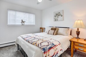 A bedroom with a bed, bedside table, lamp, window with blinds, and a wall-mounted horse decoration. - Centennial Home w/ Game Room, 11 Mi to Downtown! (Littleton)