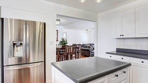 A modern kitchen with stainless steel appliances, white cabinetry, and a granite countertop. - Centennial Home w/ Game Room, 11 Mi to Downtown! (Littleton)