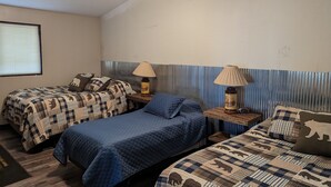Une chambre avec deux lits, un ventilateur de plafond et une fenêtre avec des stores.