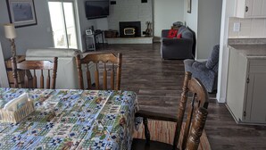 Un vaste espace de vie comprenant une cheminée, un téléviseur et une table à manger avec des chaises.