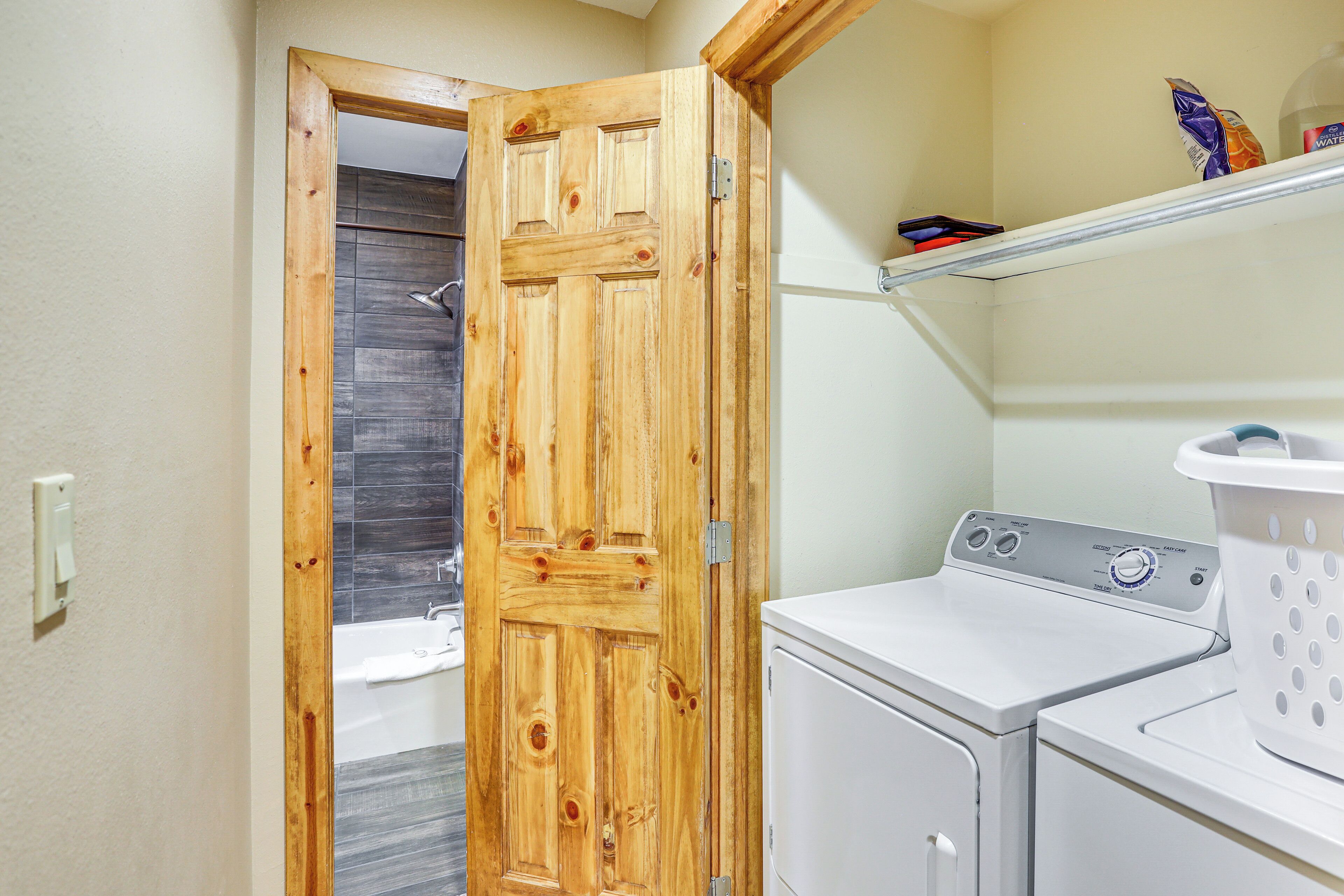 Une buanderie avec une porte en bois, un lave-linge et une étagère contenant des produits de toilette.