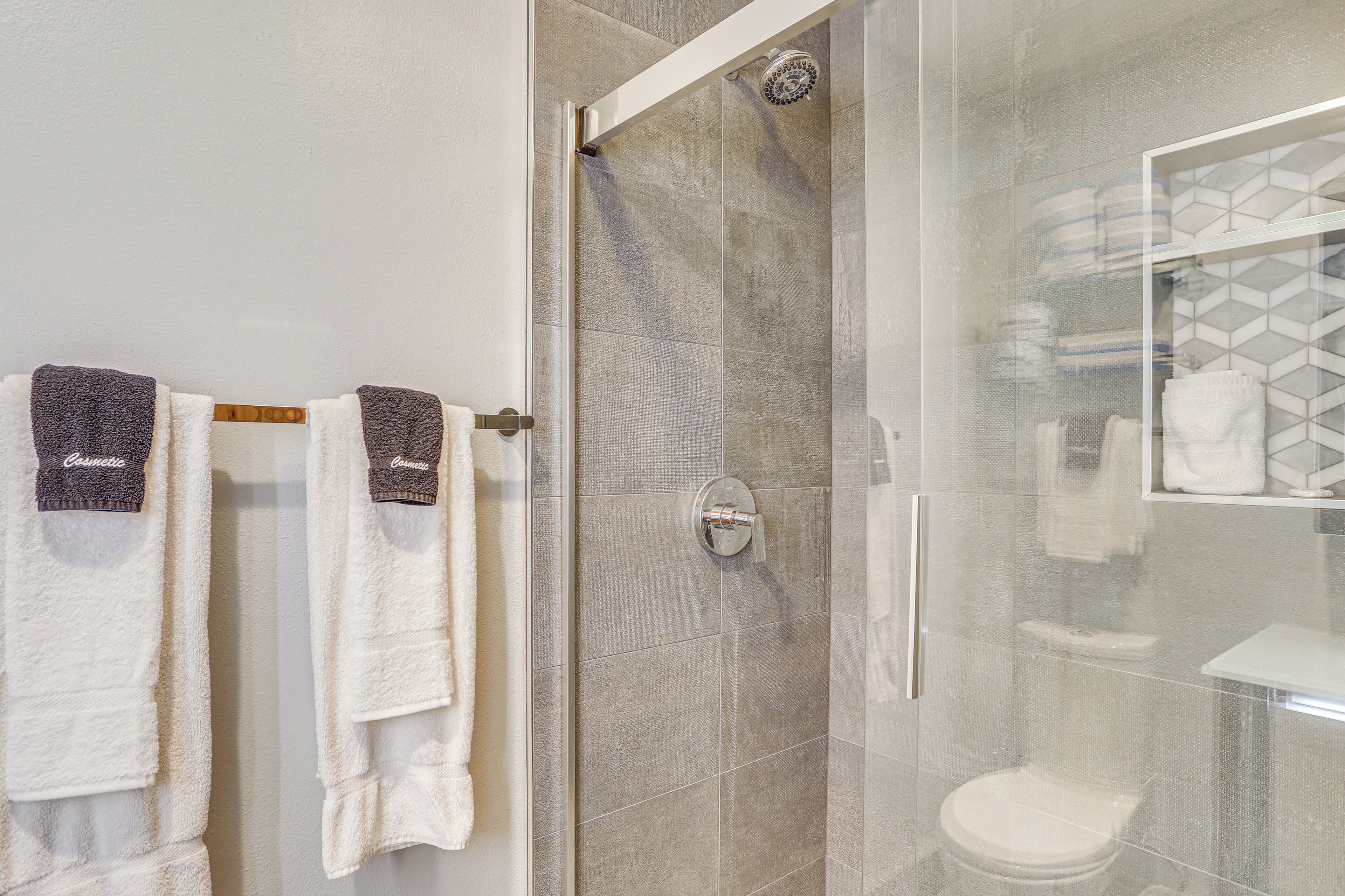 A bathroom with a glass shower enclosure, a toilet, and a glass-enclosed vanity with a mirror.