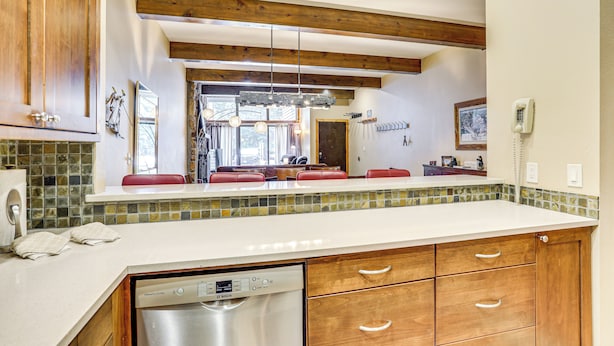 A kitchen with wooden cabinets, a dishwasher, and a tiled backsplash. - Newly Upgraded Avon Condo w/ Pool & Hot Tub Access (Avon)