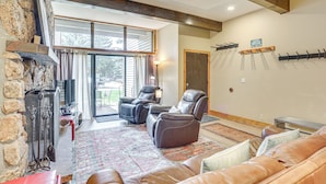 A spacious living area with leather sofas, a fireplace, and a large window offering a view of the outdoors. - Newly Upgraded Avon Condo w/ Pool & Hot Tub Access (Avon)