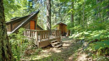Escape to a serene forest retreat with a cozy cabin-style lodging featuring a sheltered porch and easy access to the main living area.