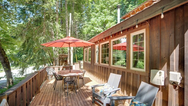 A wooden deck with outdoor furniture, including a table and chairs, and a red umbrella. - Leavenworth Cabin w/ Private Hot Tub! (Leavenworth)